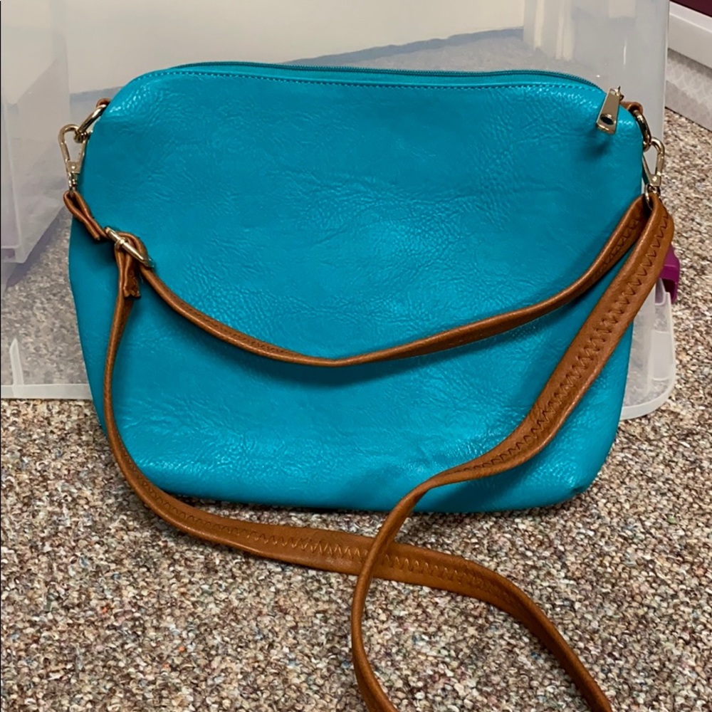 Turquoise crossbody bag with brown handles.